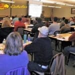 A group of people sitting at tables in front of a projector.