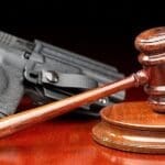 A judge 's gavel and a gun on top of a table.