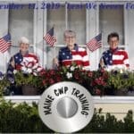Three women in patriotic clothing sitting on a window ledge.