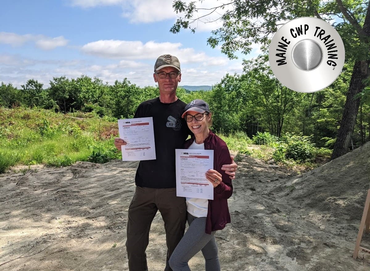 Two people holding up papers in front of trees.