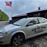 A silver car parked on top of gravel.
