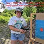 A woman holding a gun in front of an archery target.