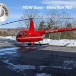 A red helicopter is on the ground near some snow.