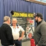Three men standing in front of a sign.