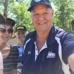 A man in a blue shirt and hat standing next to some people.
