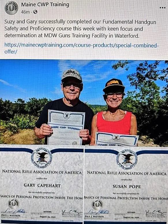 Two people holding certificates in front of a forest.