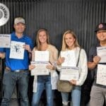 A group of people holding up papers in front of a black background.