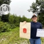 A woman holding up a bag and a sign.