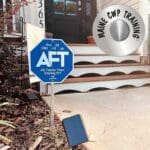 A blue sign sitting on the ground in front of a house.