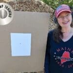 A woman standing next to a cardboard target.